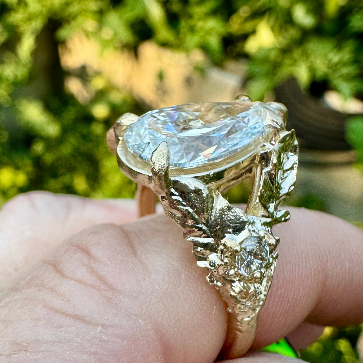 4 carat pear shaped lab diamond set in a gold ring with leaves and dandelions